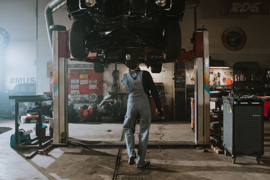 Automobile mechanic fixing a car in a repair garage, focus on service and repair work